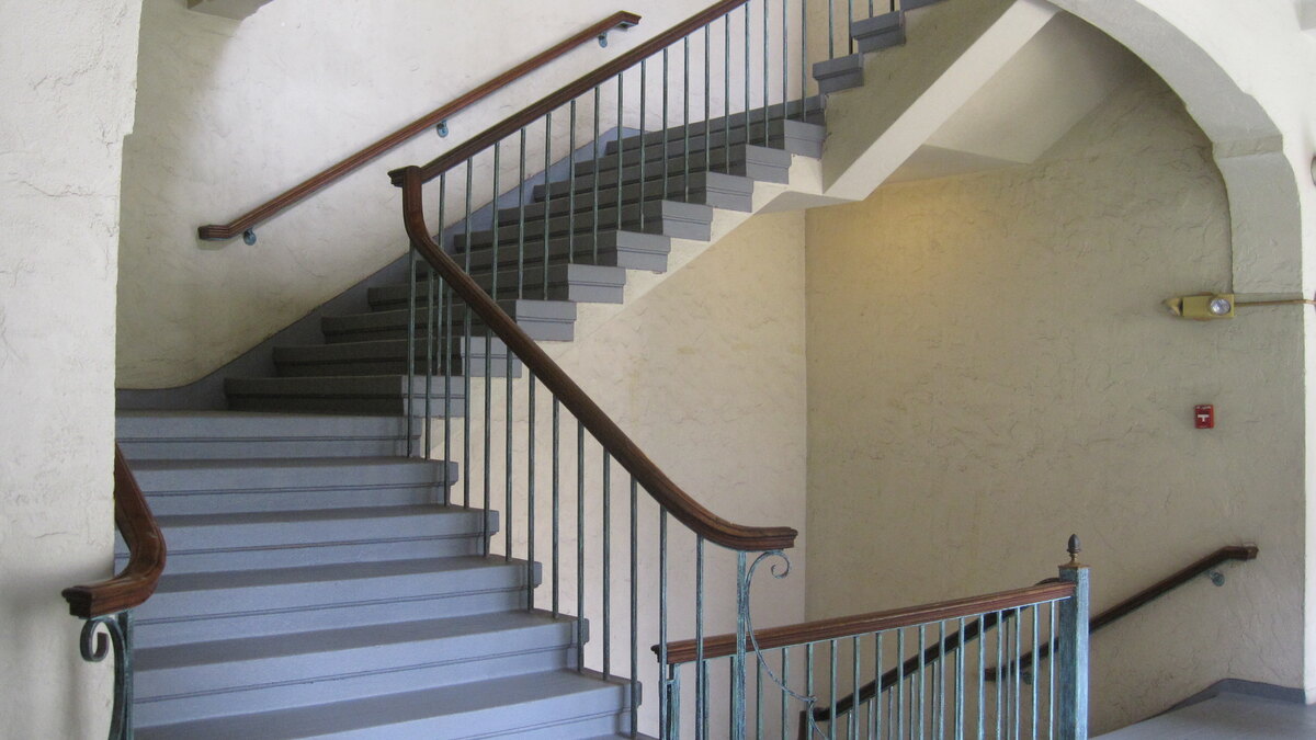 An interior stairwell and landing with wooden handrails inside Honolulu’s Laniākea YWCA building.