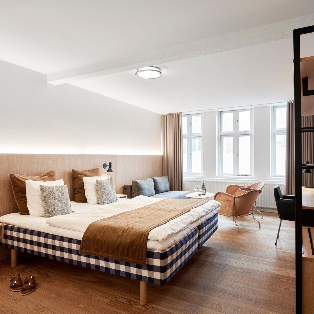 Hotel Oasia guest room with a checkered Hästens bed and pale wood floors