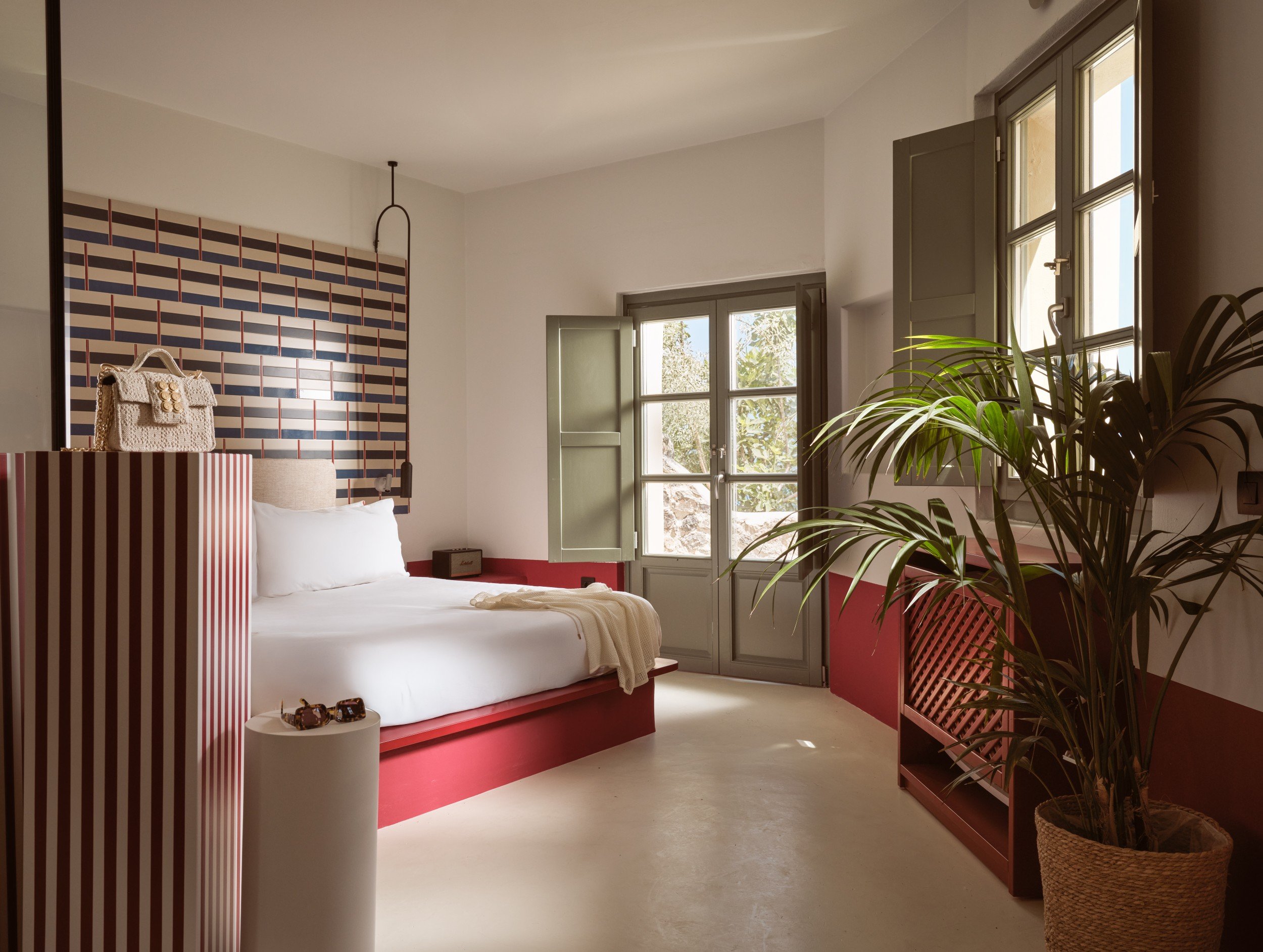 Santorini suite with a red platform bed, striped headboard, and French doors