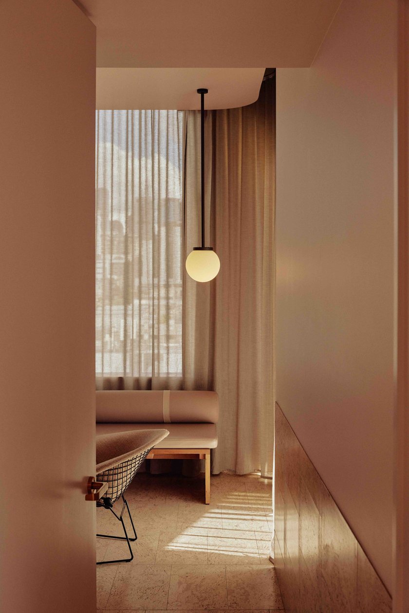 Soft pink interior with a curved bench and pendant light