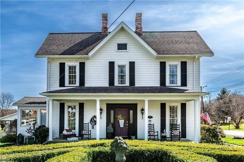 A white 1800s farmhouse with black shutters and a full front porch at 397 Evans City Road