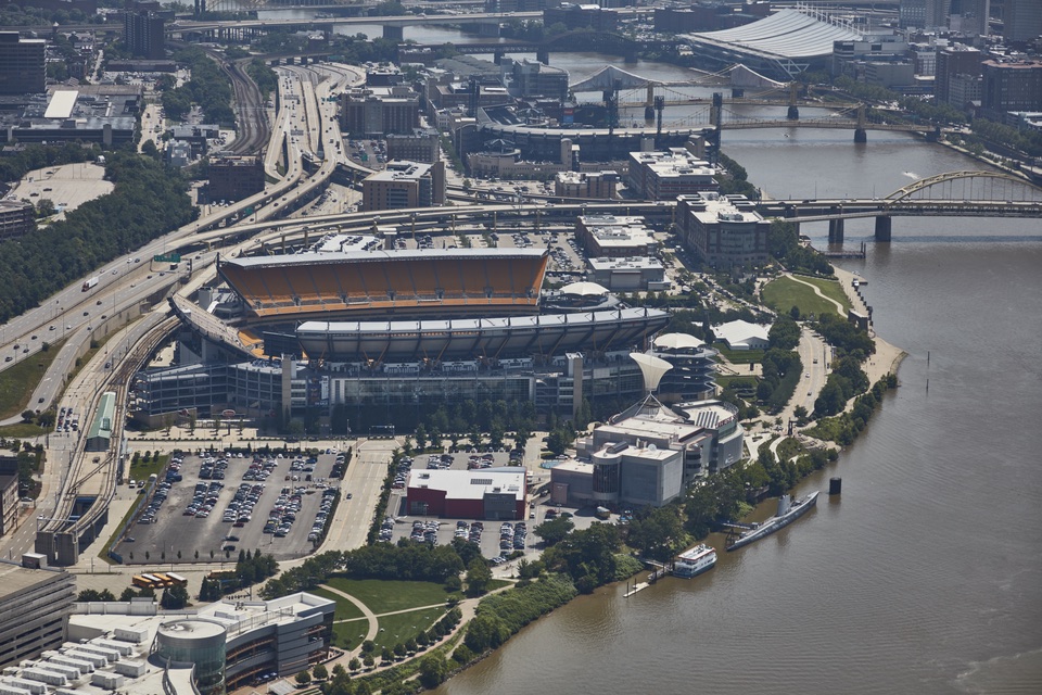 Aerial photo of the Steelers' stadium on the North Shore, its yellow seats open to the sky, with the Ohio River and the Allegheny bridges behind it