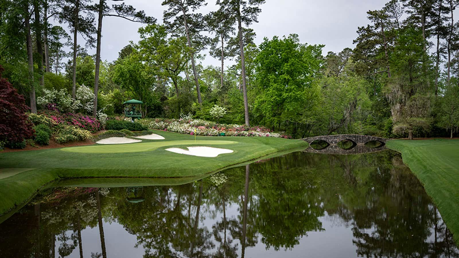 Augusta National Golf Club scenic view with green, bunkers, water, and stone bridge