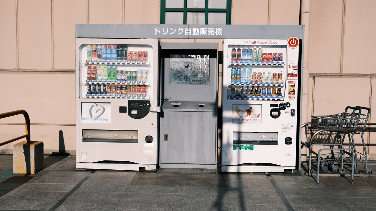 Two drinks vending machines side by side on a Japanese street