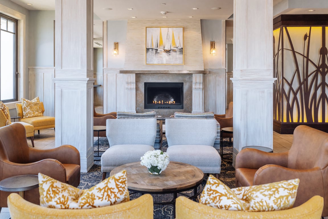 Coastal hotel lounge with fireplace, blue seating, and patterned pillows