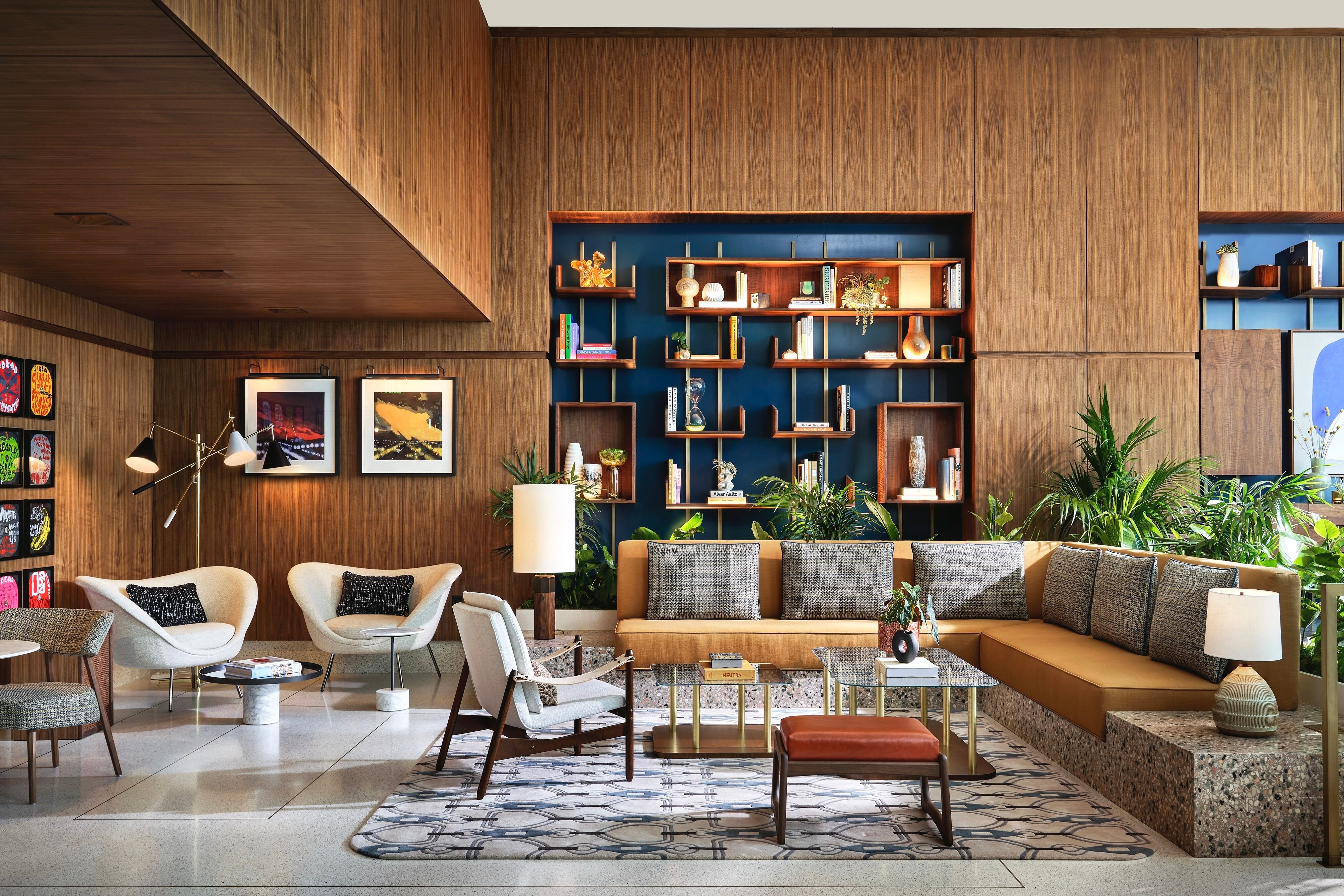 Wood-paneled lobby with lounge chairs, bookshelves, and plants