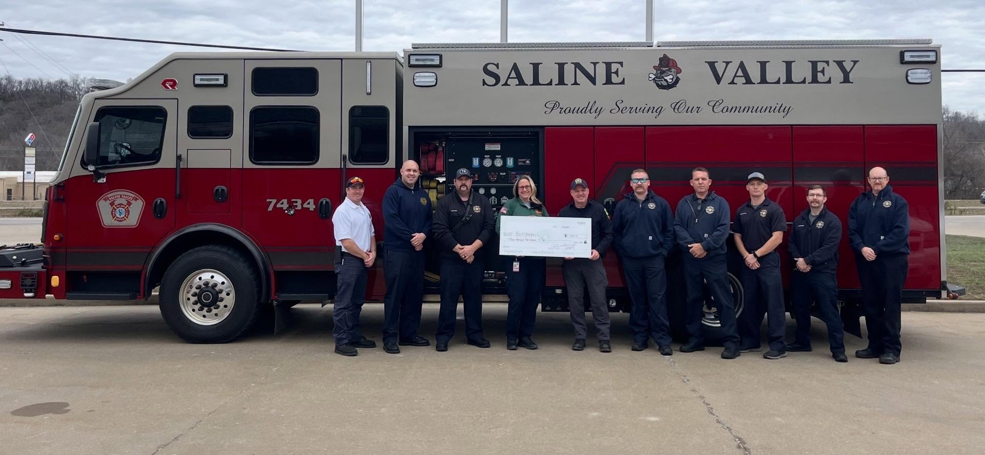 BackStoppers supporters and first responders standing with a donation check in front of a fire truck