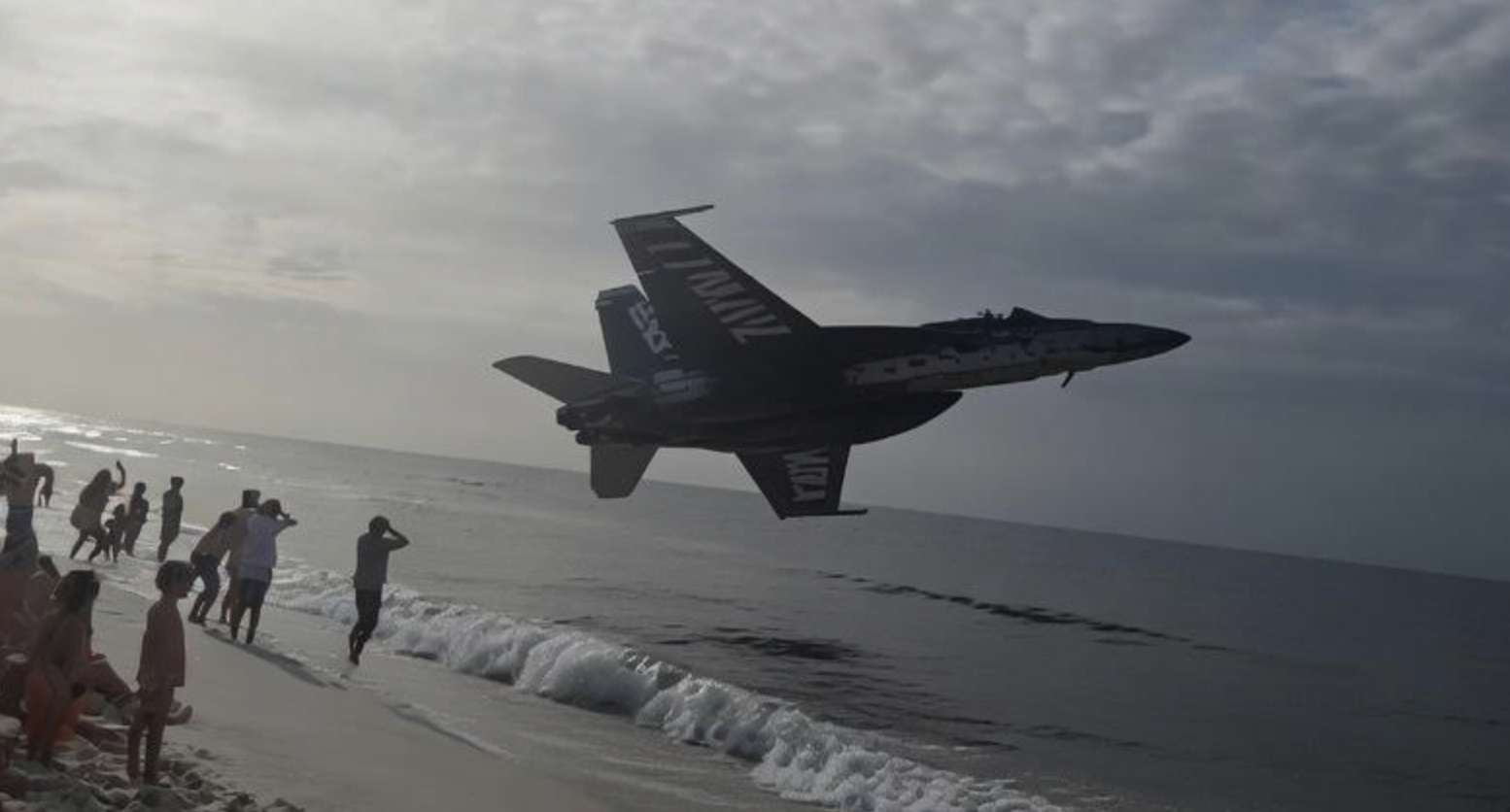 A Blue Angels jet buzzing a beach with a wake that forgot to touch the water