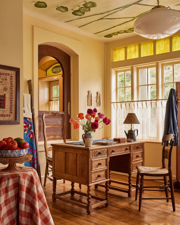 An antique wooden desk and yellow-trimmed windows beneath a painted ceiling at The Six Bells Countryside Inn.