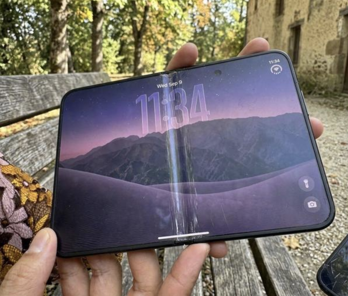 A folding phone with heavy wear down the middle of its screen, an AI-made image posted a day after the phone was announced