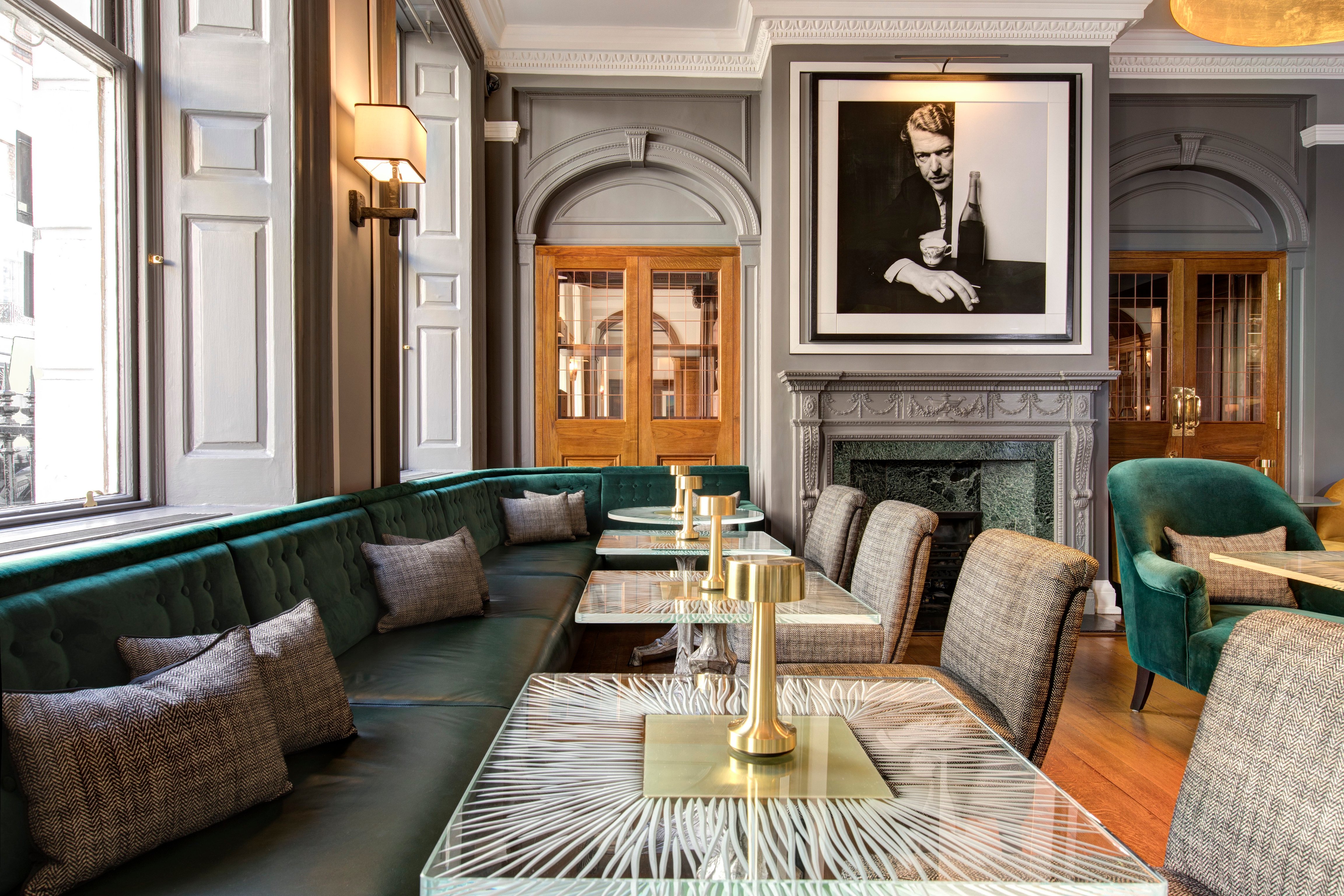 Green velvet seating and photographs in a bar at Brown’s Hotel