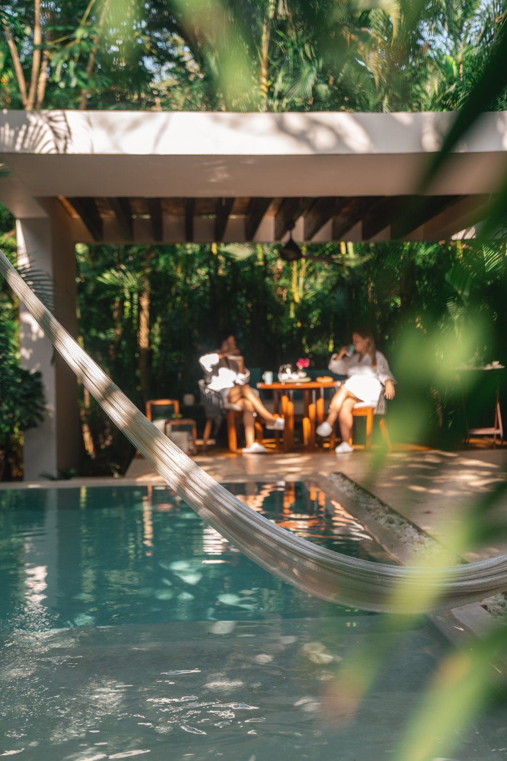 Guest relaxing in a hammock above a jungle-framed pool