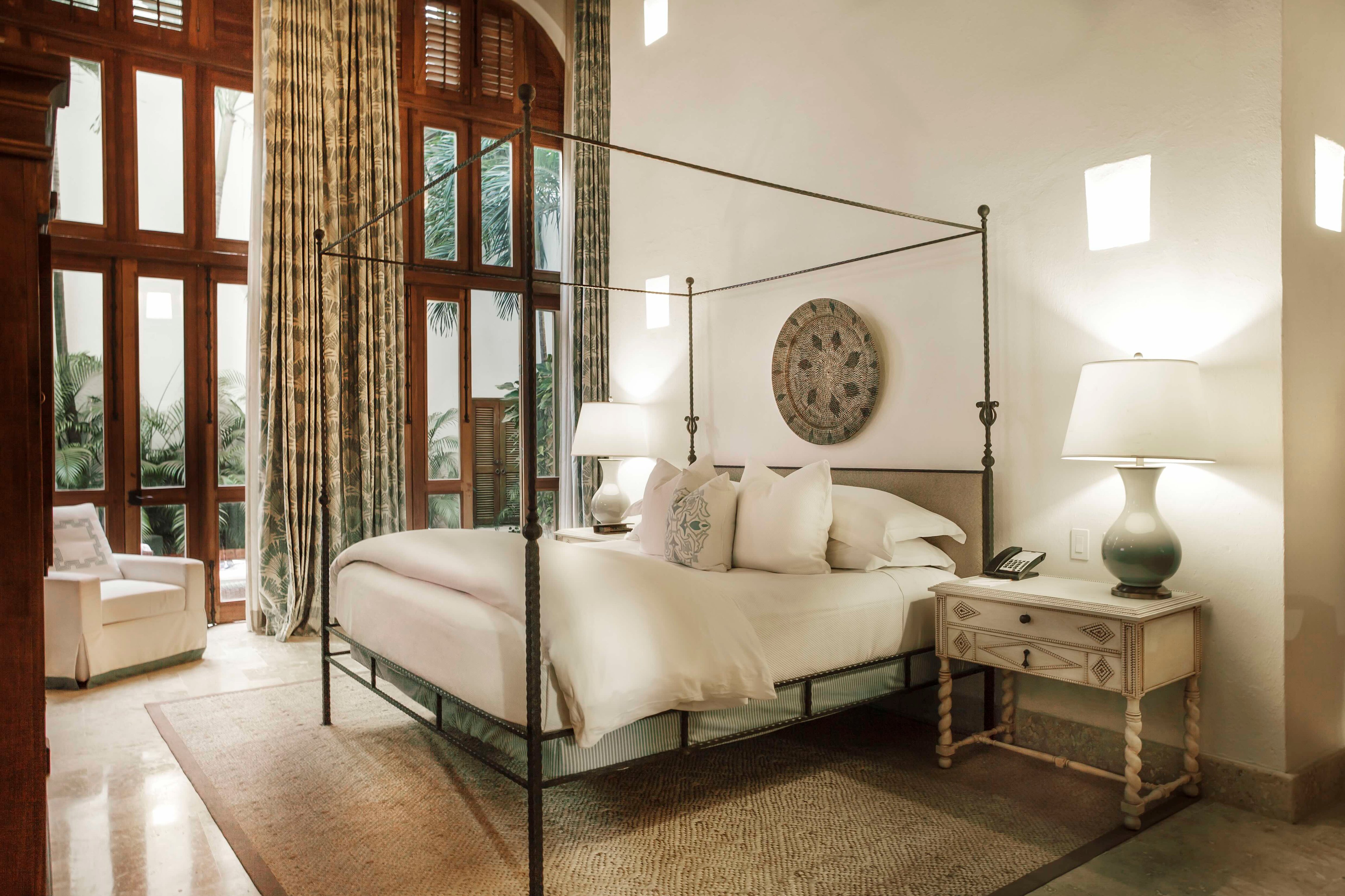 Four-poster bed and tall windows in a Casa San Agustín guest room