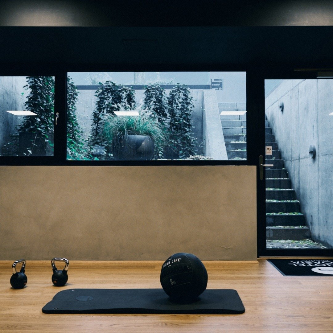 Minimalist basement gym with exercise mat, weights, and garden-level windows