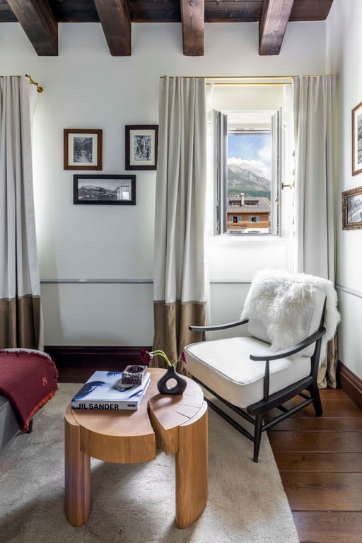 Guest room seating beneath timber beams with a mountain view