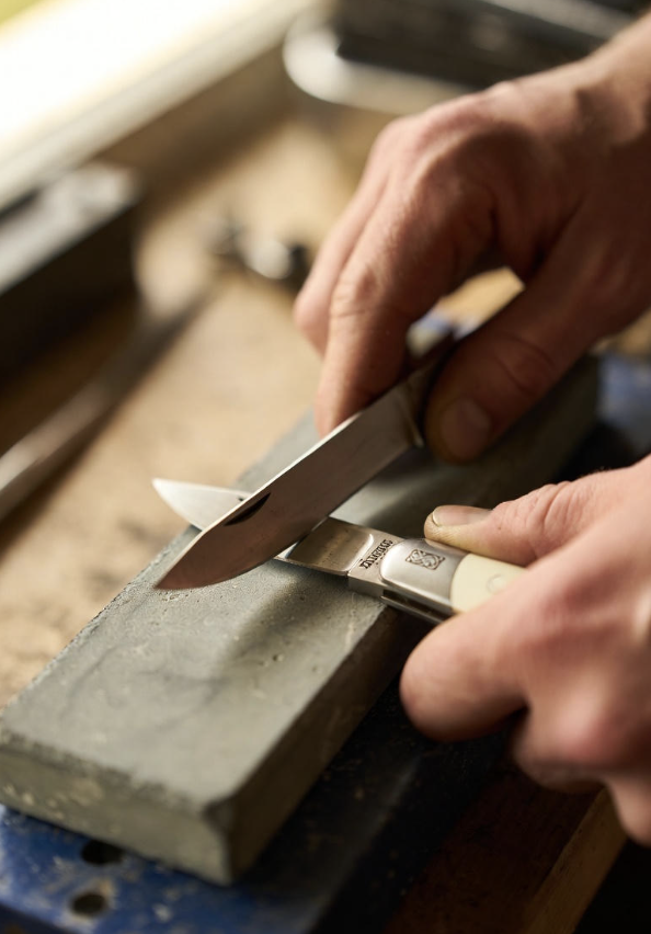 Hand sharpening a pocket knife on a stone