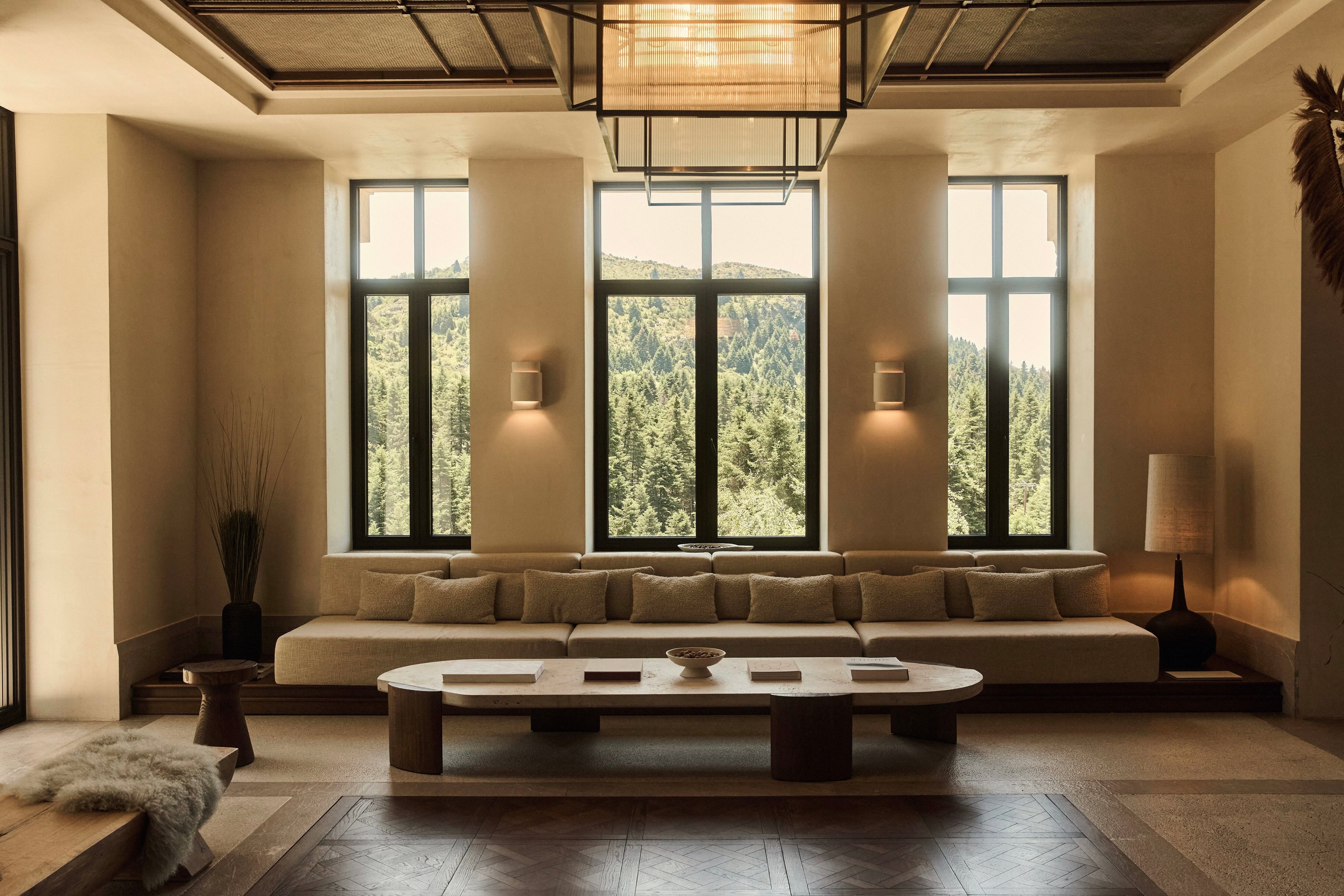 High-ceilinged lounge with long sofas and forest-facing windows