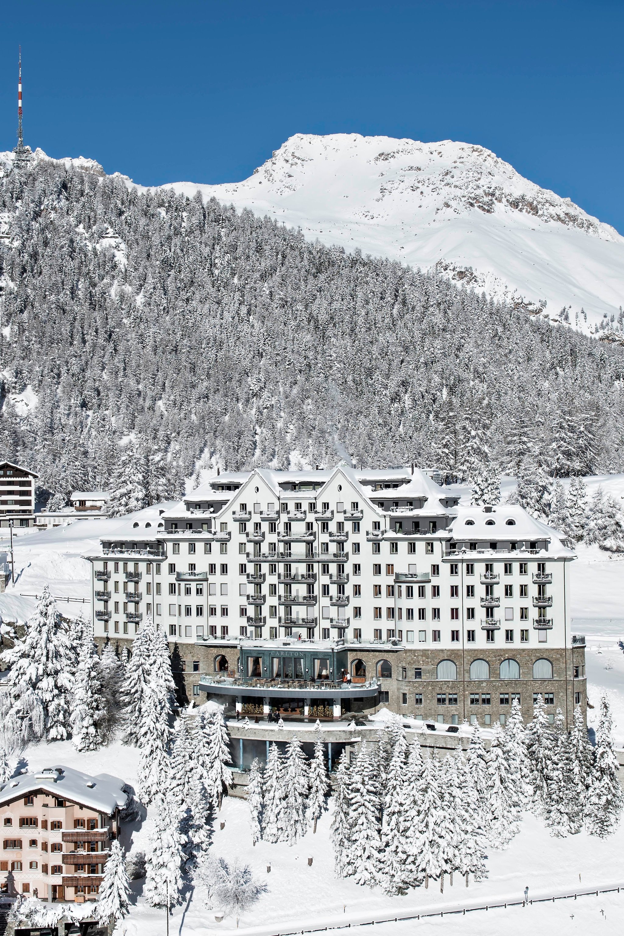 Carlton Hotel St. Moritz against a forested winter mountainside