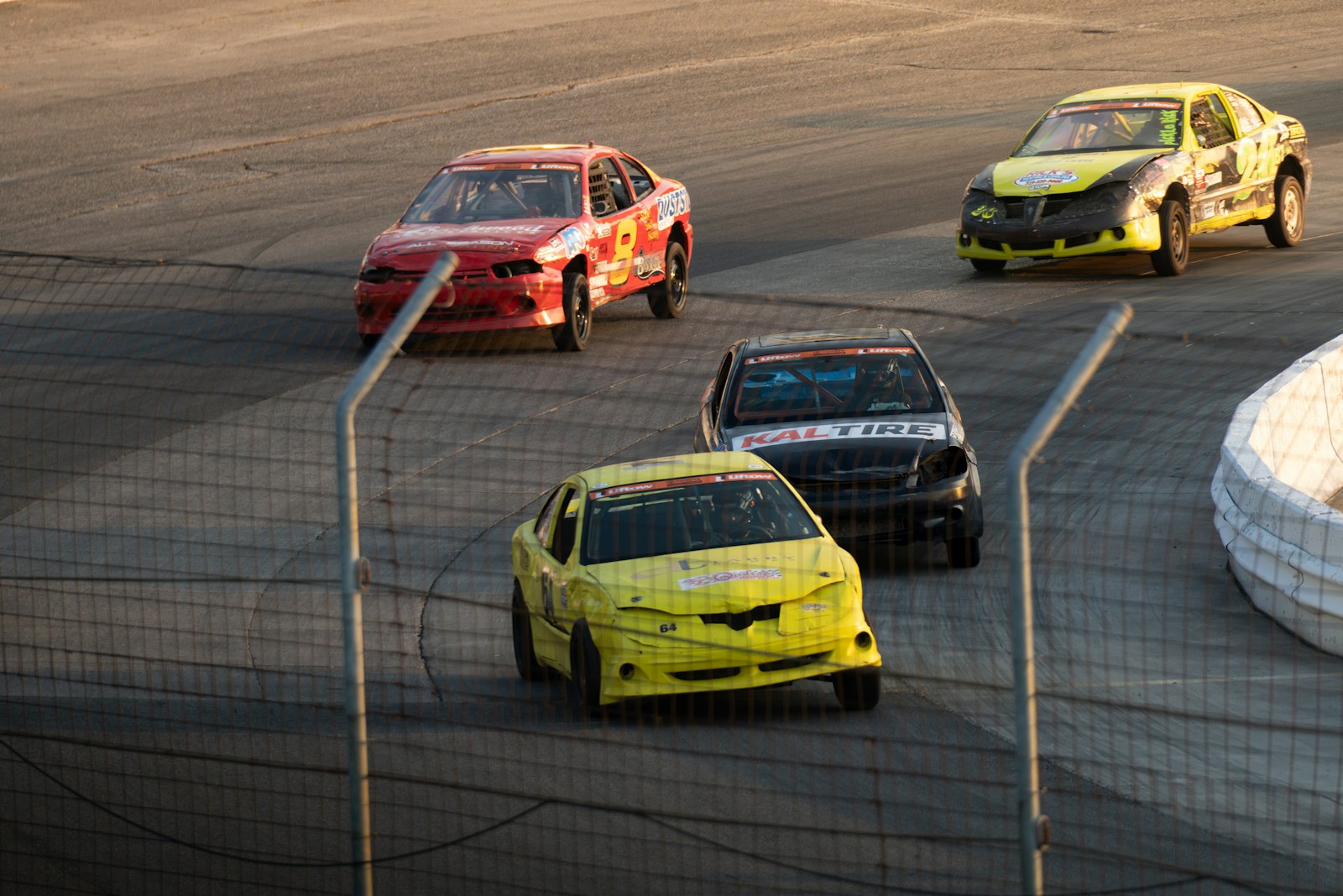 Four stock cars racing on an asphalt track
