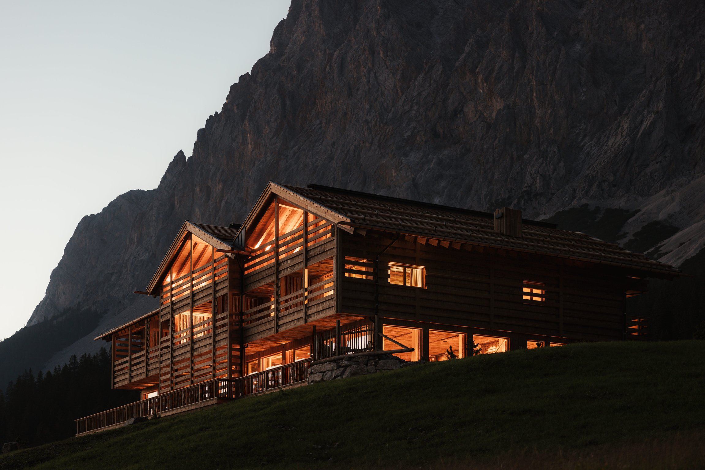 Timber Eriro Hotel glowing beneath a steep Tyrolean mountain