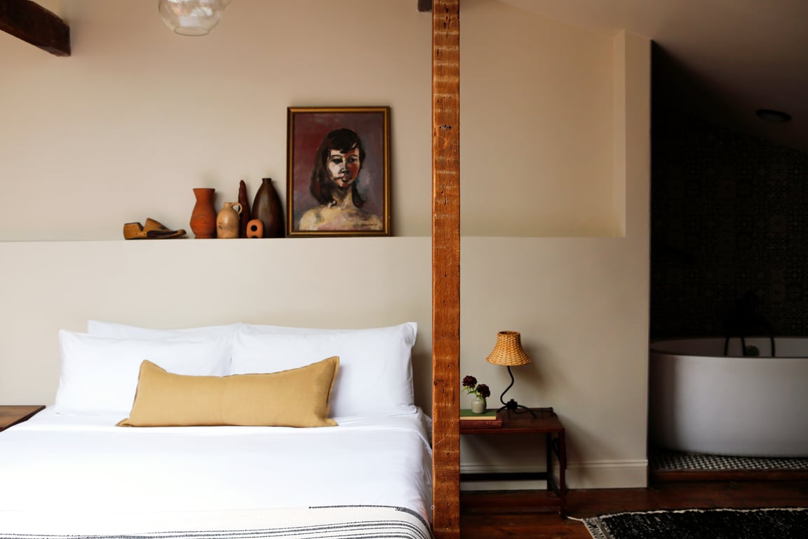 Guest room with white bedding and curated artwork at Kingston Carriage House