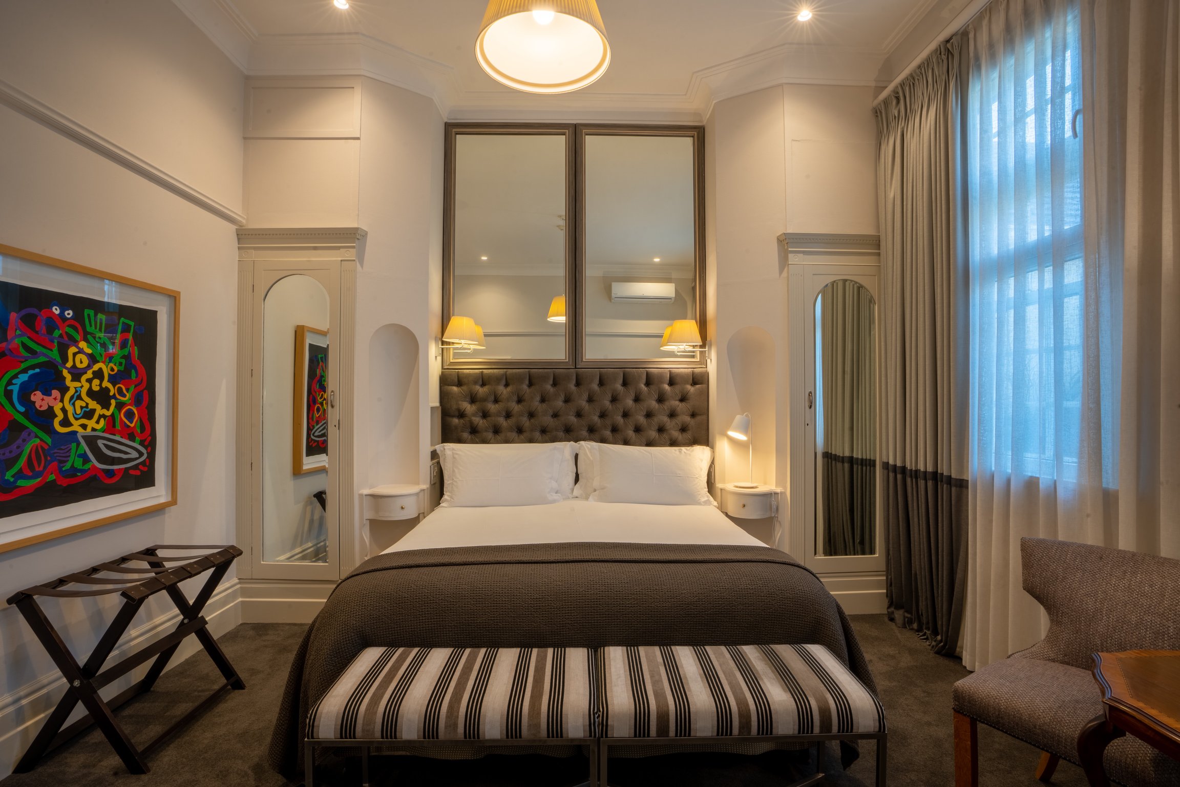 Elegant Ellerman House guest room with upholstered bed and striped bench