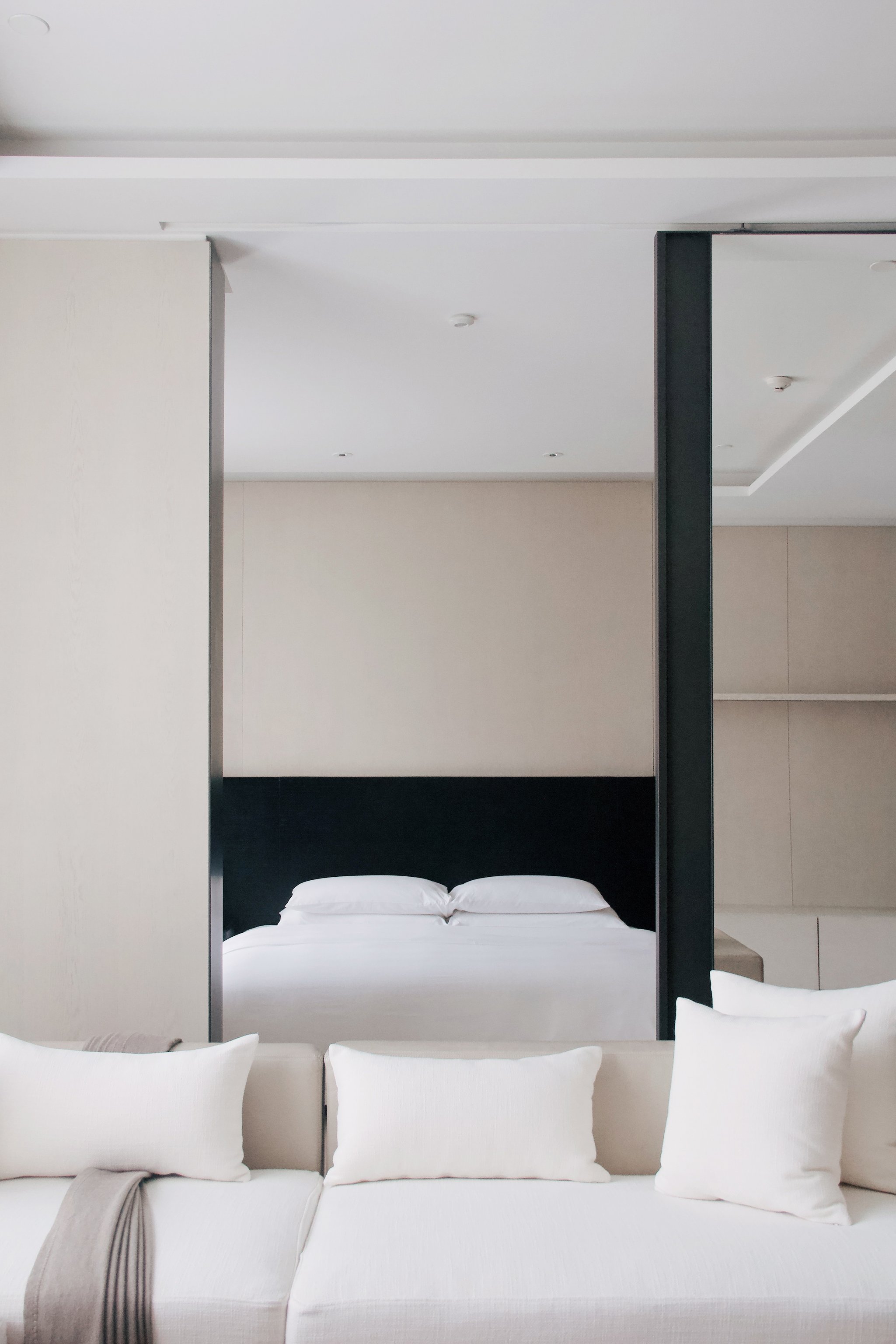 Minimalist white guest room with a tall black bed frame