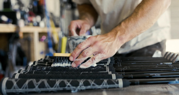 Hands scrubbing a golf club grip with a brush