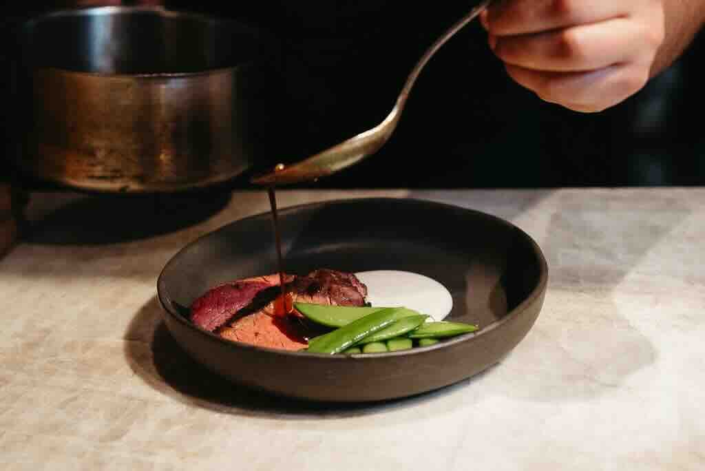 Chef finishing a plated dish at Hotel Britomart
