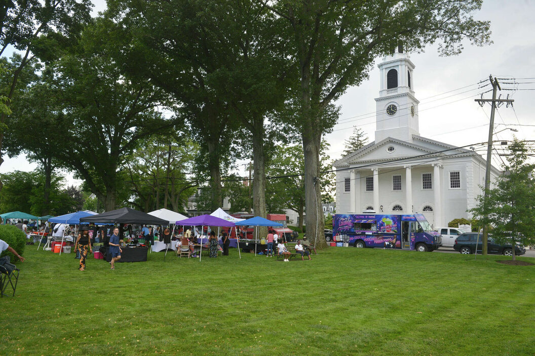Vendor tents, food trucks and a crowd on the Norwalk Town Green during a past Celebration of Juneteenth, with the white church steeple in the background.