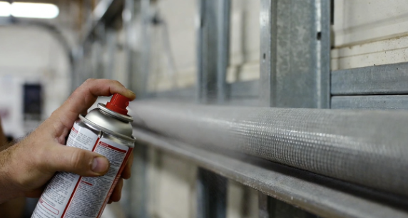 Hand spraying lubricant on garage door rollers