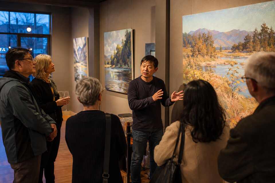 An artist discussing landscape paintings during a gallery opening in Richmond BC