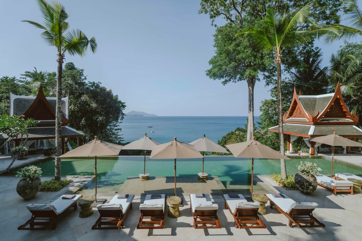 Palm-fringed pool and loungers overlooking the sea at Trisara Phuket