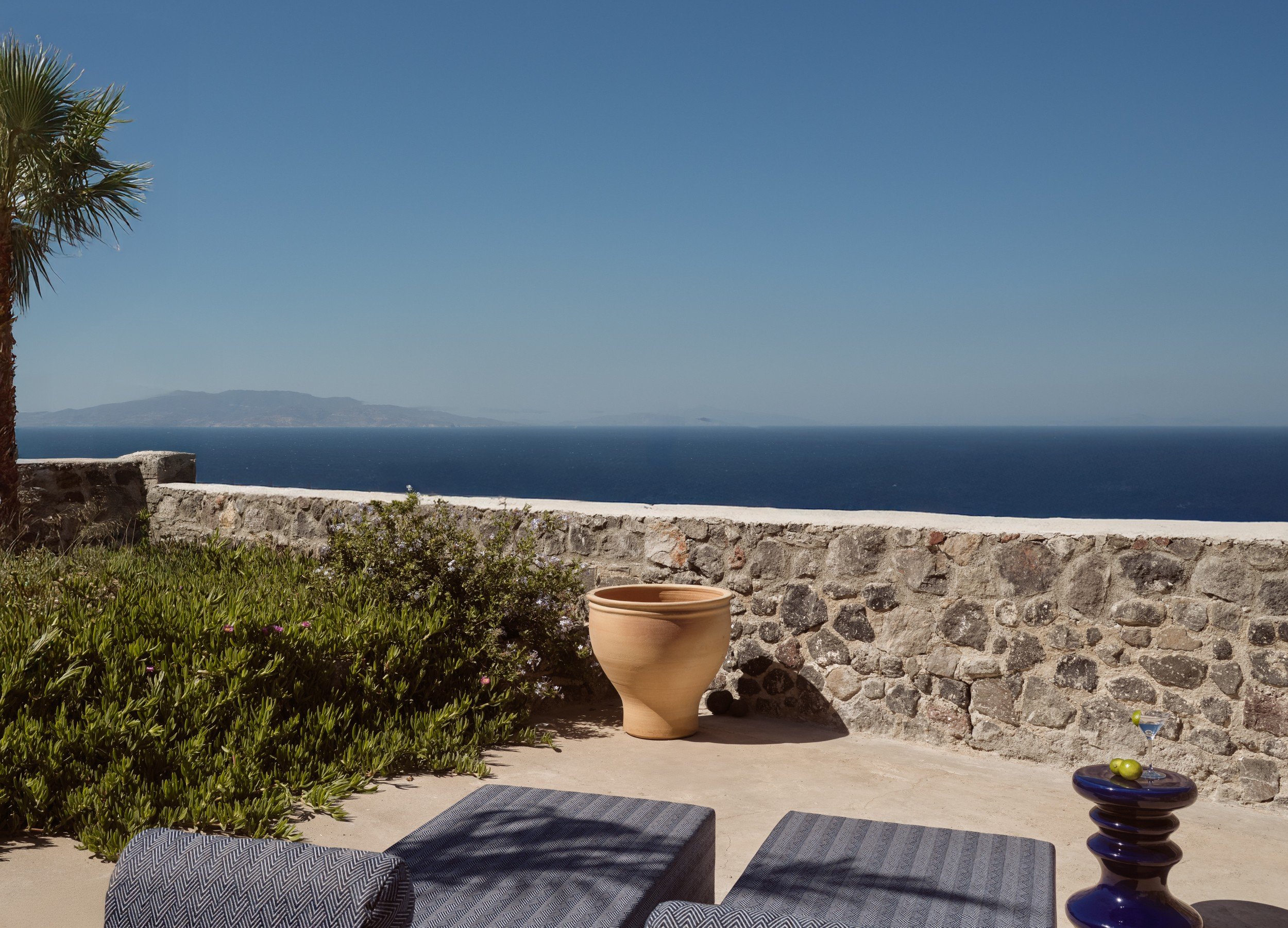 Stone terrace with low seating and a wide Aegean Sea view