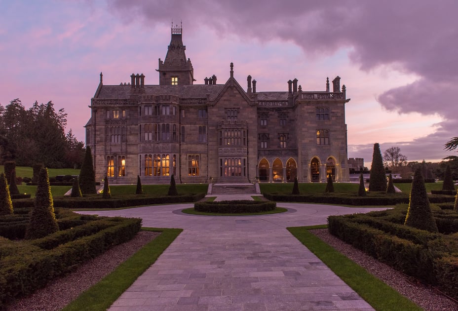 Adare Manor's neo-Gothic facade and formal gardens at dusk