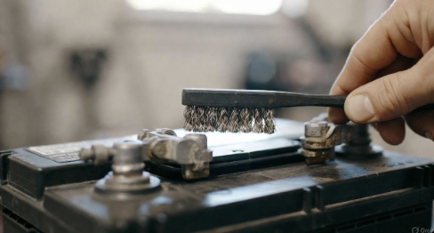 Car battery terminals being cleaned with a small brush