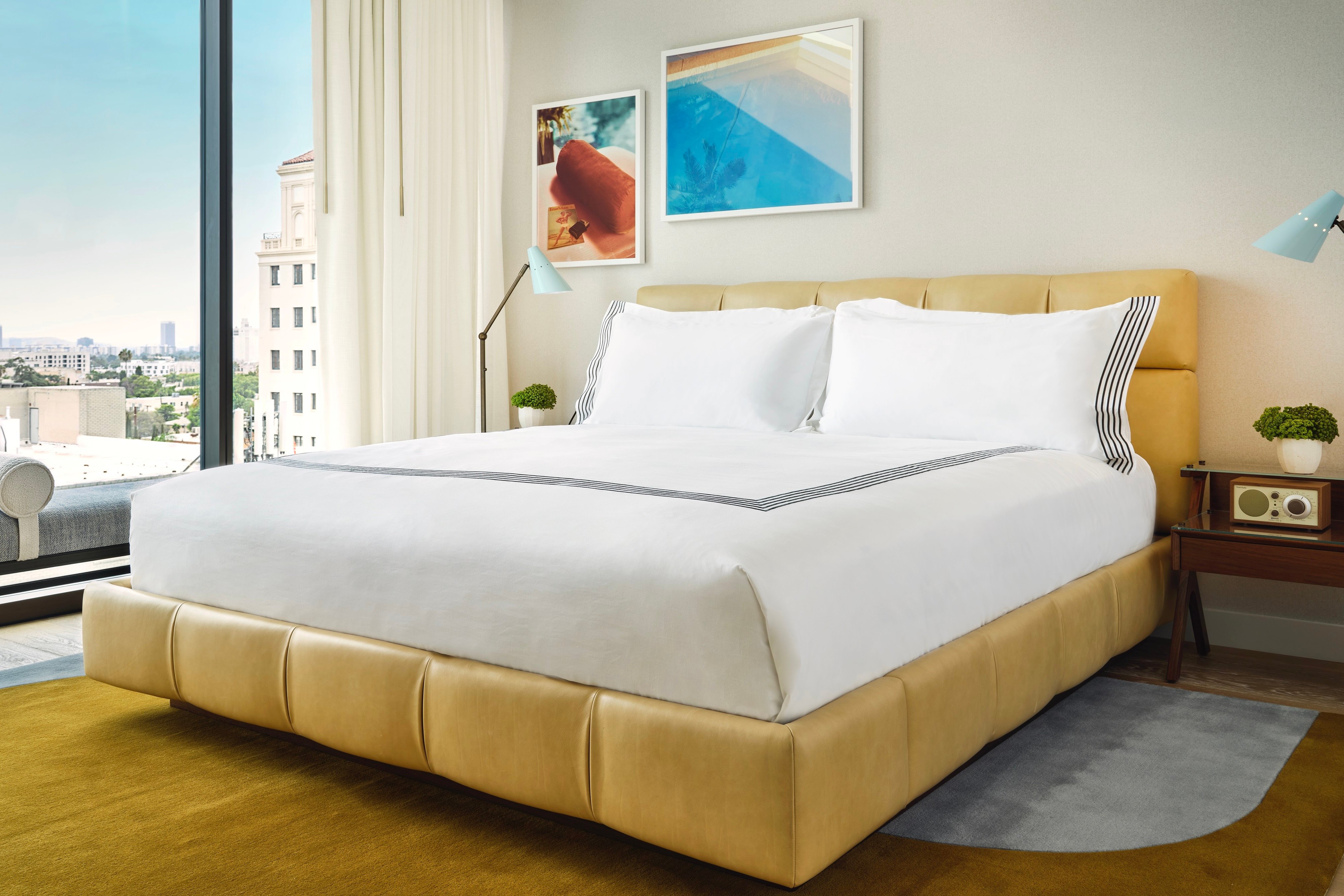 Bright guest room with a white bed, golden rug, and floor-to-ceiling windows