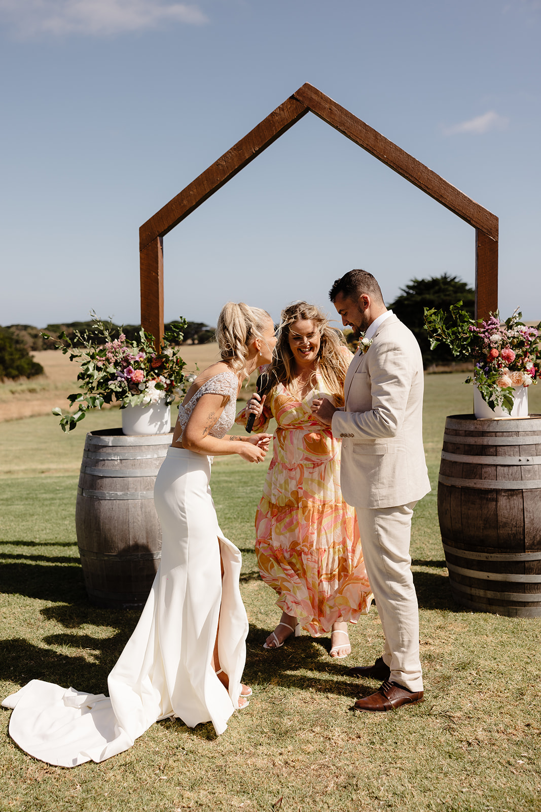 Karlee marrying a laughing couple beneath a floral arch