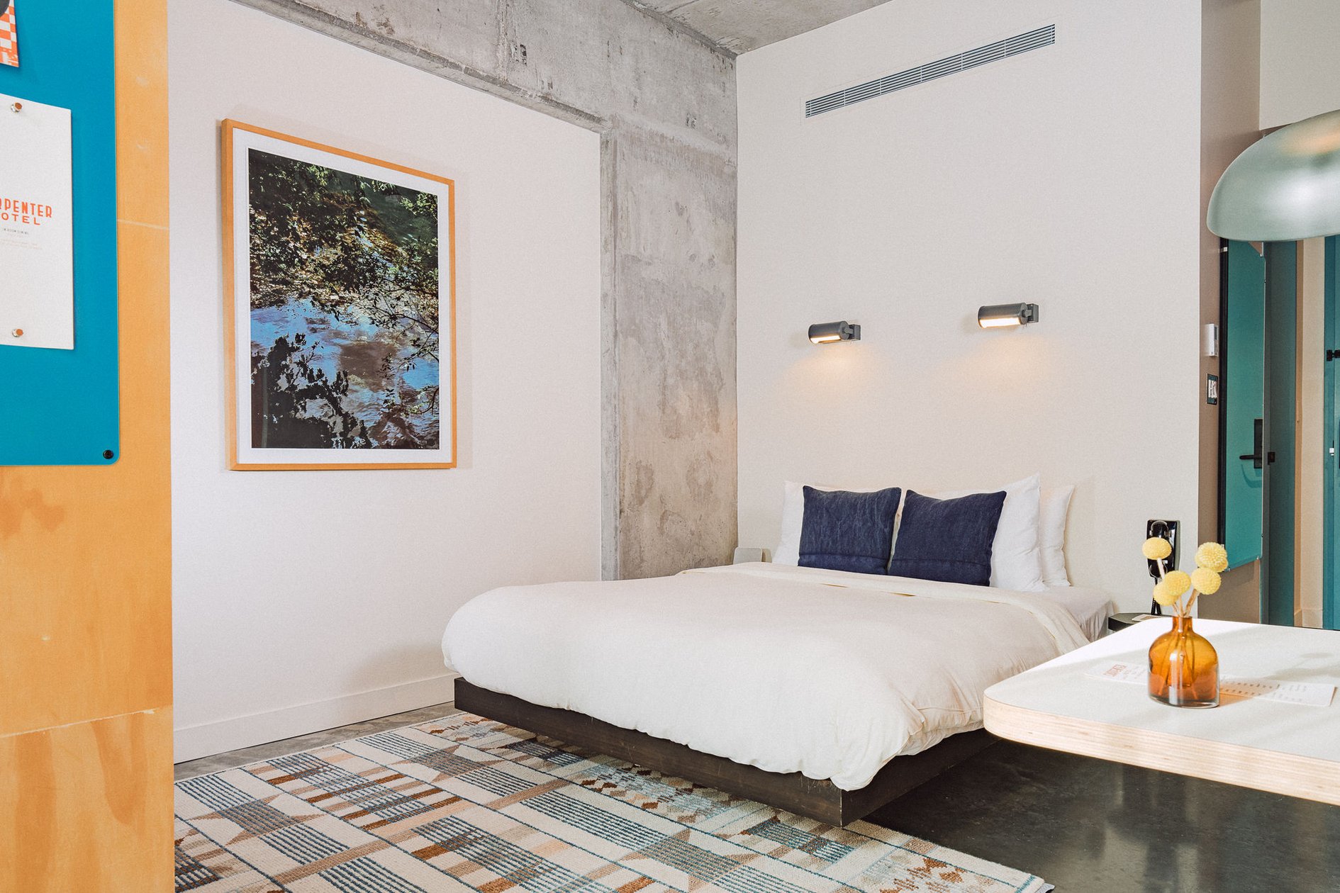 Carpenter Hotel guest room with a concrete wall and white linens