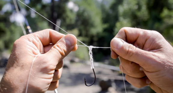 Hands tying a fishing knot with clear steps visible