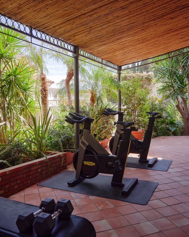 Outdoor exercise bikes in a leafy fitness area at Villa Sant’Andrea
