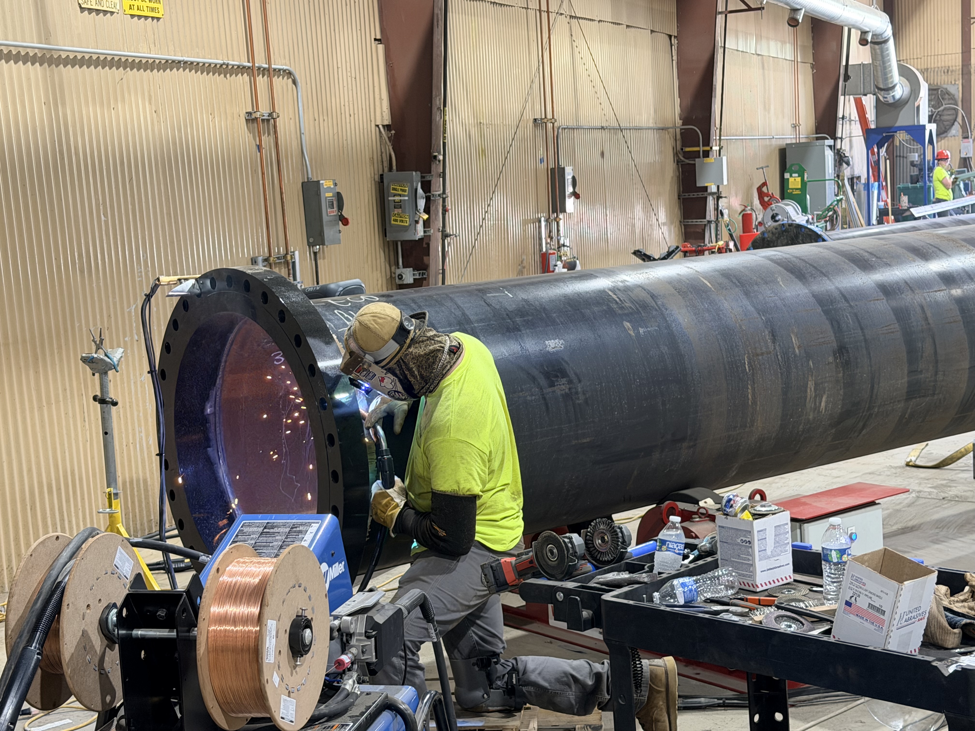 Worker welding a large section of industrial piping