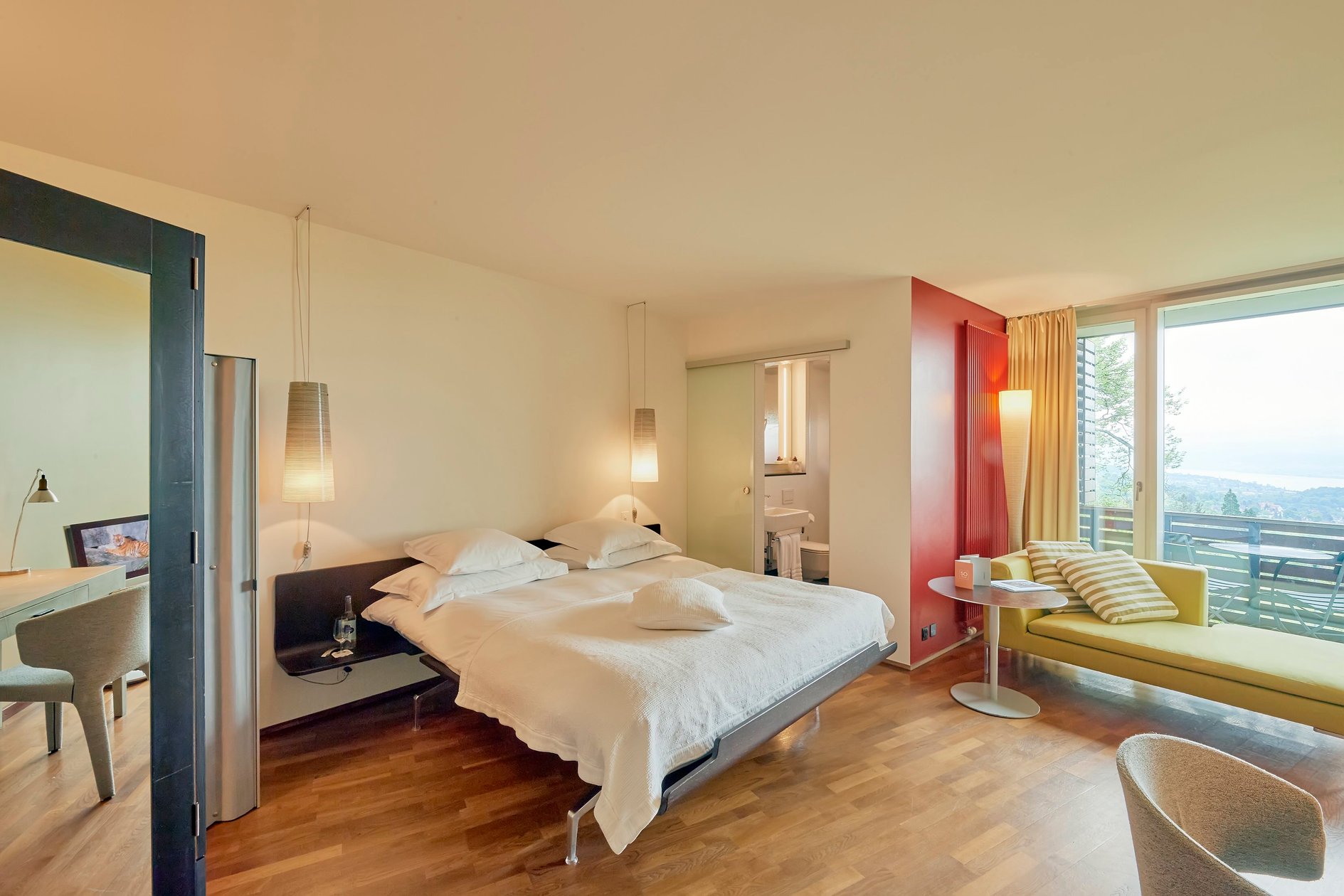 Guest room with warm wood flooring and a view over Zurich