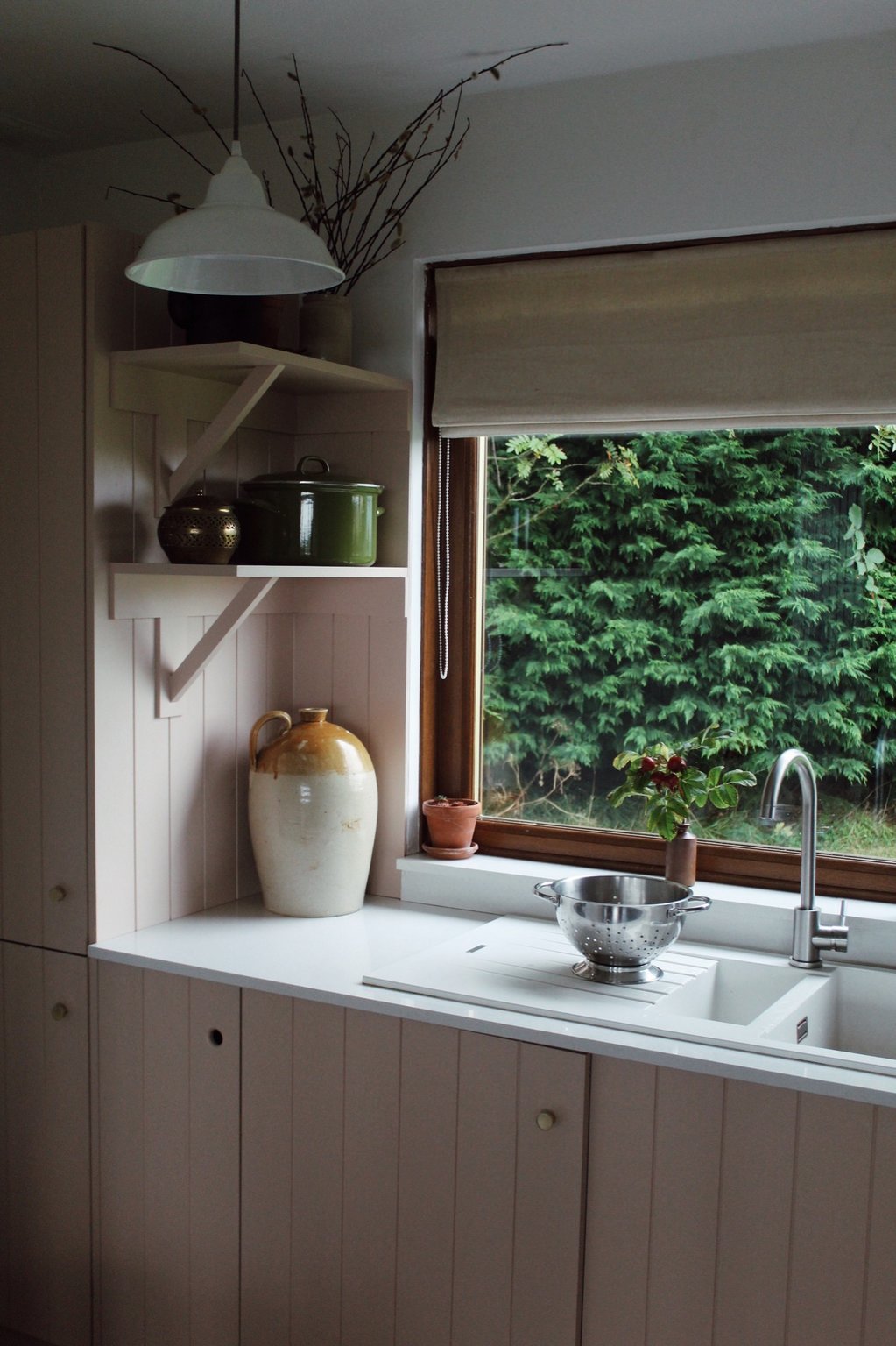 Self-catering kitchen sink beneath a window overlooking dense greenery