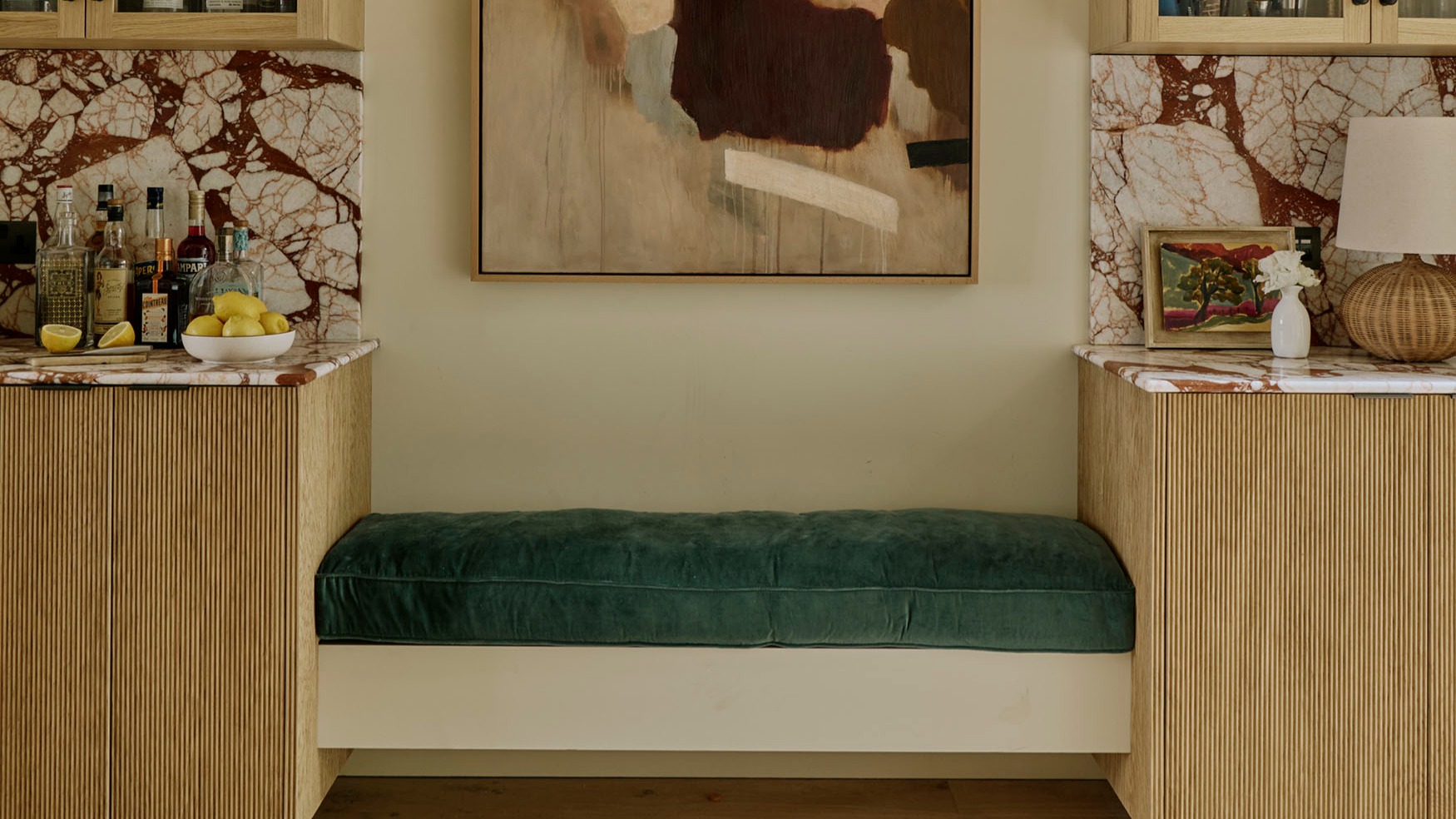 A green upholstered bench between reeded oak cabinets in Studio Squire’s Belsize Park project.