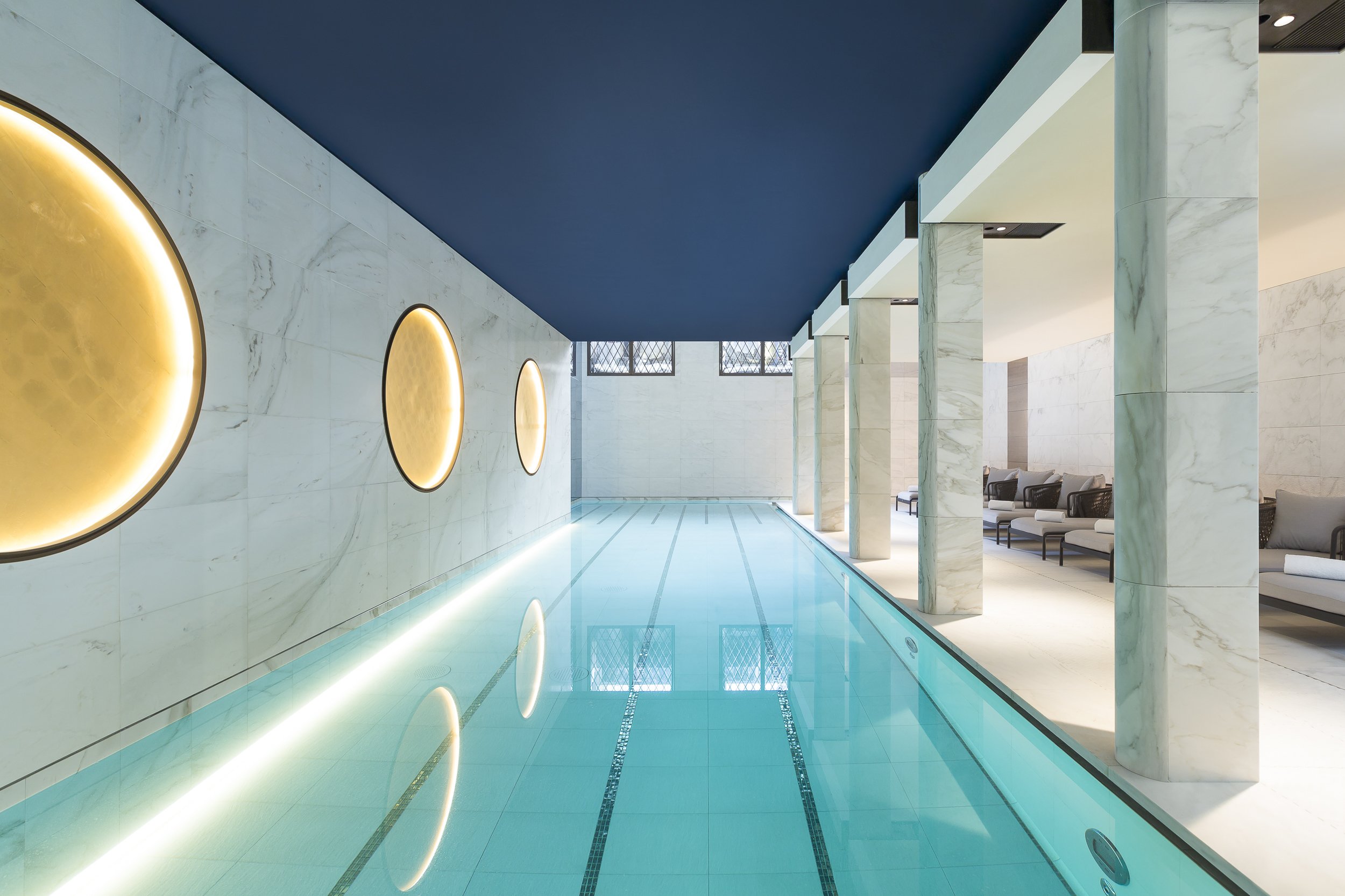 Indoor pool with circular wall lights at Hôtel Lutetia’s Akasha Spa