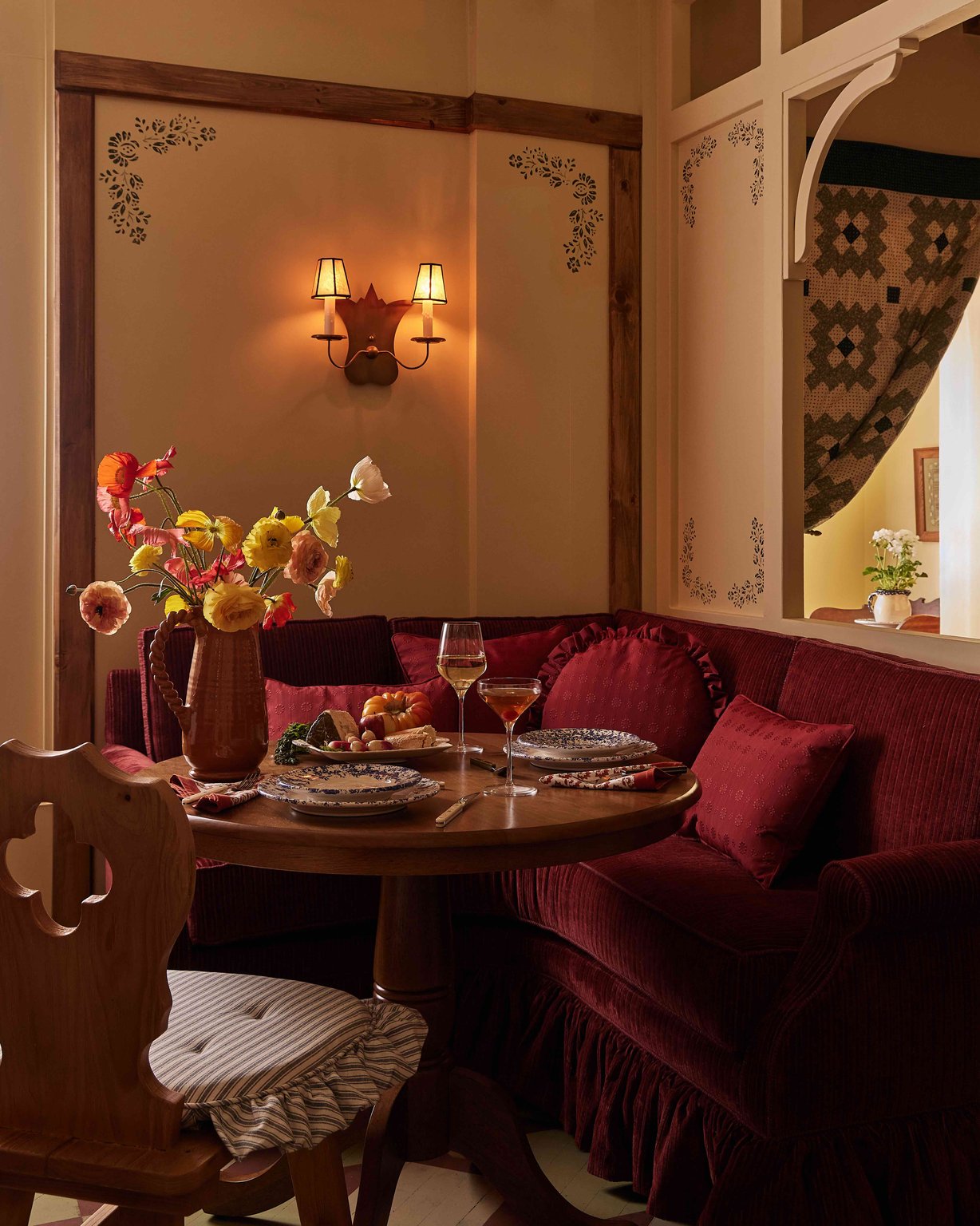 A candlelit table beside a burgundy banquette in the restaurant at The Six Bells Countryside Inn.