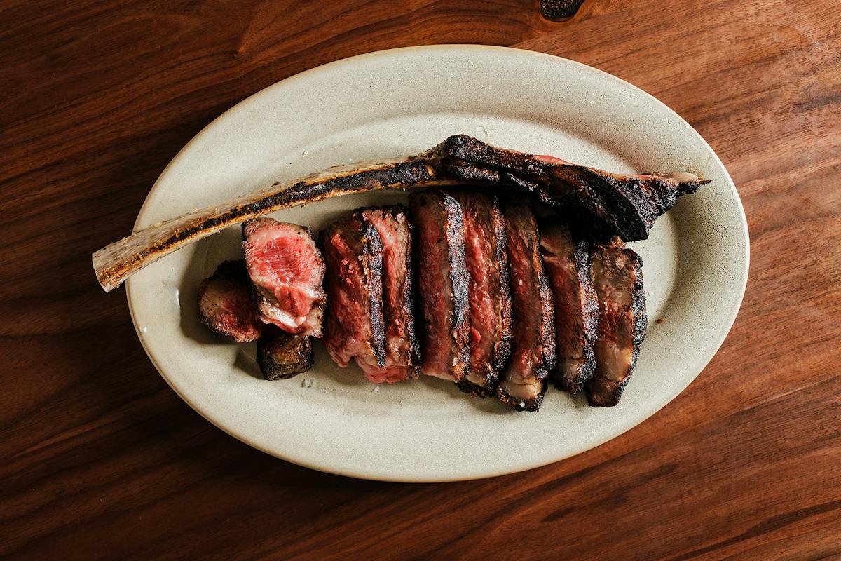 Sliced bone-in steak on a platter at Hacienda Tulum