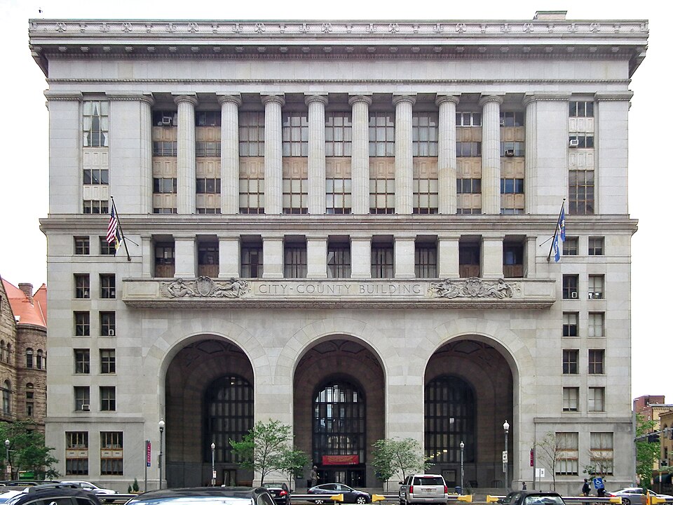 The City-County Building on Grant Street, Downtown Pittsburgh: a granite facade with tall columns above three arched entrances, flags on either side