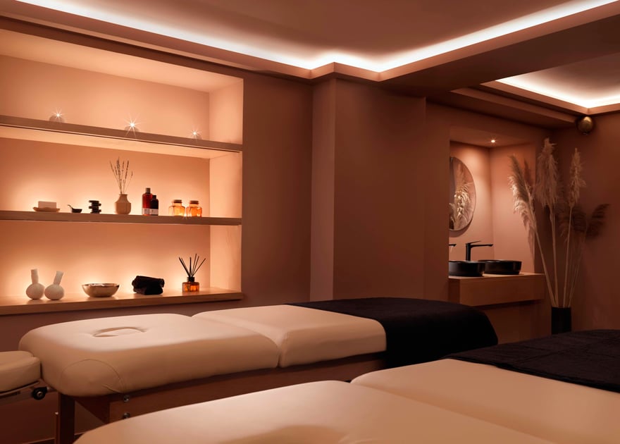 Warmly lit treatment room with two massage beds